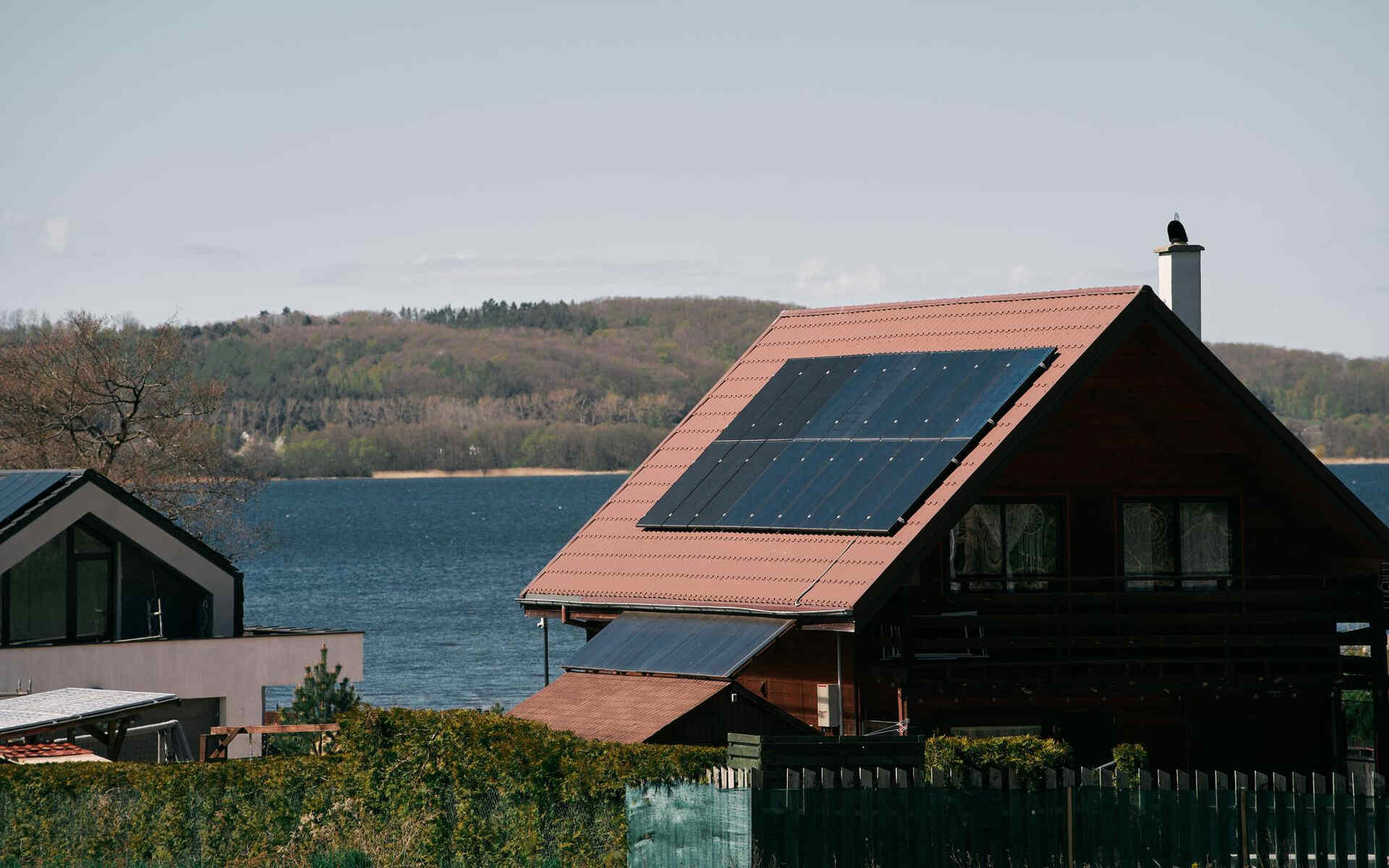 A lakeside home with rooftop solar panels, showcasing energy independence solutions for residential living.